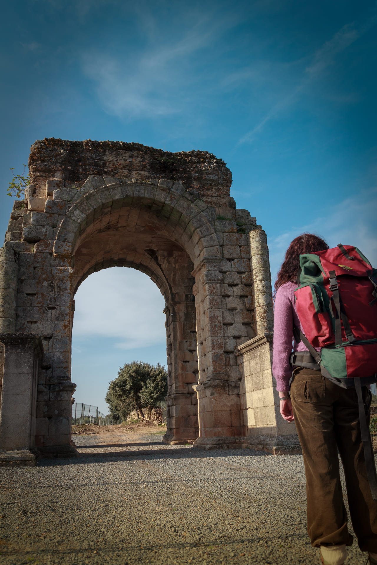 peregrina recorriendo la via de la plata junto al arco romano de cáparra